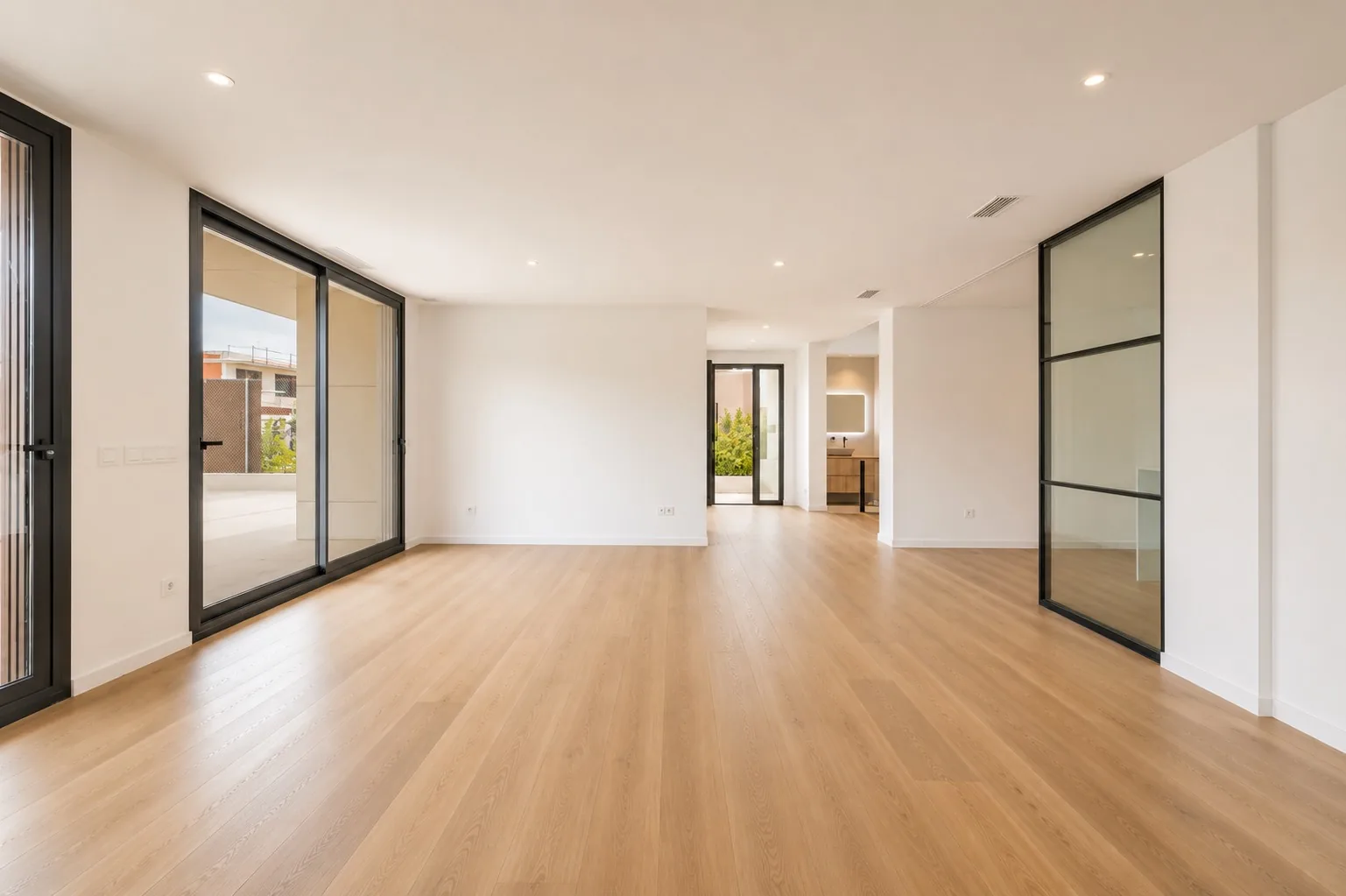 Salón diáfano de la Homi Alfinach con suelo de roble y vidriera negra